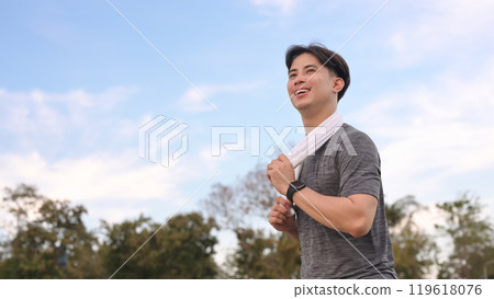 Smiling young sporty man jogging on a path surrounded by nature Smiling young sporty man jogging on a path surrounded by nature 119618076