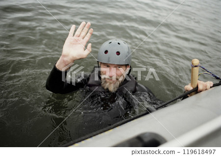Film portrait of joyful bearded man falling in lake and waving at camera enjoying water sports by boat copy space Film portrait of joyful bearded man falling in lake and waving at camera enjoying water sports by boat copy space 119618497