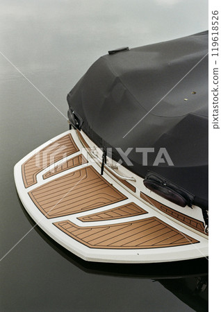 Minimal retro film shot of motor boat covered by protective tent with focus on back boarding deck in dark lake water Minimal retro film shot of motor boat covered by protective tent with focus on back boarding deck in dark lake water 119618526