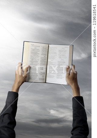 Man holding a opened holy bible in his hand. Symbol of faith and worship in God. People christianity prayer 119618541