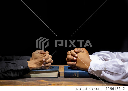 Man praying together with his hands on a holy bible on wooden table. Symbol of faith and worship in God. People christianity prayer in church 119618542