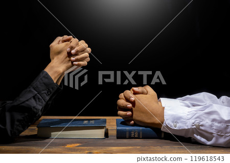 Man praying together with his hands on a holy bible on wooden table. Symbol of faith and worship in God. People christianity prayer in church 119618543
