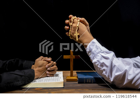 Man praying together with rosary beads, religion cross and holy bible on wooden table. Symbol of faith and worship in God. People christianity prayer in church 119618544