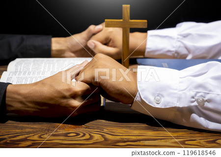 Man praying together with religion cross and on a opened holy bible. Symbol of faith and worship in God. People christianity prayer in church Man praying together with religion cross and on a opened holy bible. Symbol of faith and worship in God. People christianity prayer in church 119618546