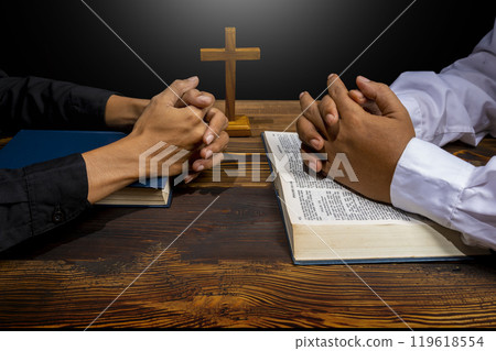 Man praying together with religion cross and on a opened holy bible. Symbol of faith and worship in God. People christianity prayer in church Man praying together with religion cross and on a opened holy bible. Symbol of faith and worship in God. People christianity prayer in church 119618554