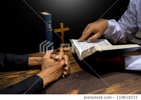 Man praying together with religion cross and on a opened holy bible. Symbol of faith and worship in God. People christianity prayer in church Man praying together with religion cross and on a opened holy bible. Symbol of faith and worship in God. People christianity prayer in church 119618555