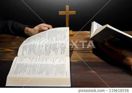 Man praying together with religion cross and on a opened holy bible. Symbol of faith and worship in God. People christianity prayer in church Man praying together with religion cross and on a opened holy bible. Symbol of faith and worship in God. People christianity prayer in church 119618556