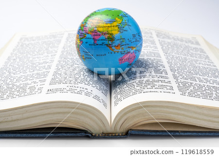 Opened book of Holy Bible with globe. It is laying on white background. Symbol of faith and worship in God 119618559