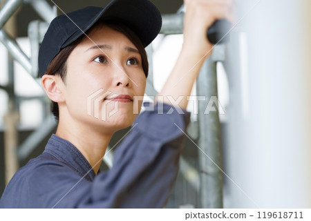 A female craftsman applying paint to plasterboard with a trowel 119618711