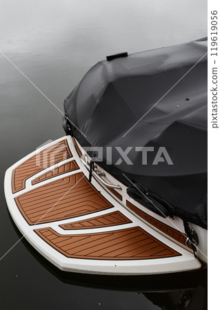 Minimal shot of motor boat covered by protective tent with focus on back boarding deck in dark lake waters Minimal shot of motor boat covered by protective tent with focus on back boarding deck in dark lake waters 119619056