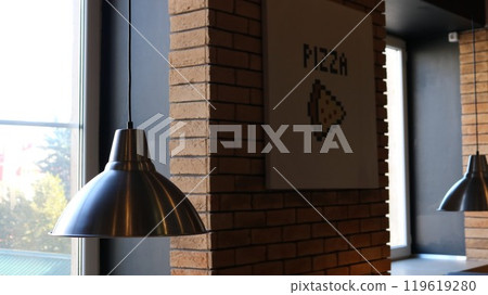 Metal hanging round lamps in cafe or pizzeria against brick wall and window, cafeteria or restaurant interior as food background 119619280