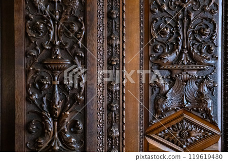 Elaborate woodwork on an antique door highlights detailed carvings of floral and animal motifs, revealing expert craftsmanship from earlier centuries, rich in history. Elaborate woodwork on an antique door highlights detailed carvings of floral and animal motifs, revealing expert craftsmanship from earlier centuries, rich in history. 119619480