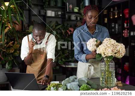 Waist up portrait of two young people working together in flower shop and managing delivery orders Waist up portrait of two young people working together in flower shop and managing delivery orders 119620256
