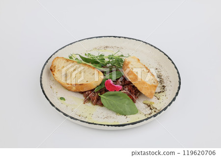 Veal tartare with dry wheat bread on a white plate on a white background Veal tartare with dry wheat bread on a white plate on a white background 119620706