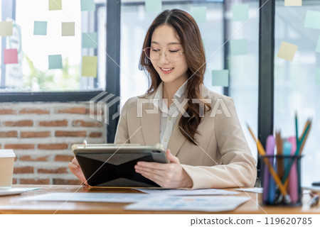 Happy young business woman working on her project at the office Happy young business woman working on her project at the office 119620785