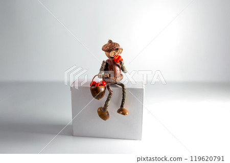acorn figurine appears to be eating one of the red berries from the basket. whimsical, detailed figure showcasing creativity and craftsmanship with natural elements. DIY, white background 119620791