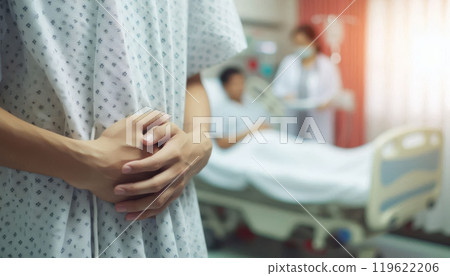Close-up of patient hands in a hospital gown with medical staff and another patient in the background. Healthcare and medical treatment concept 119622206