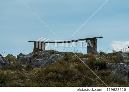Rustic wooden bench on rocky hilltop 119622826