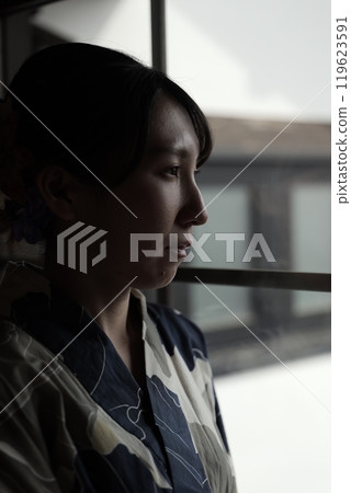 A woman in a yukata standing at a lattice door 119623591