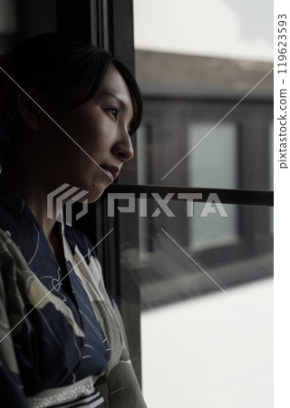 A woman in a yukata standing at a lattice door 119623593