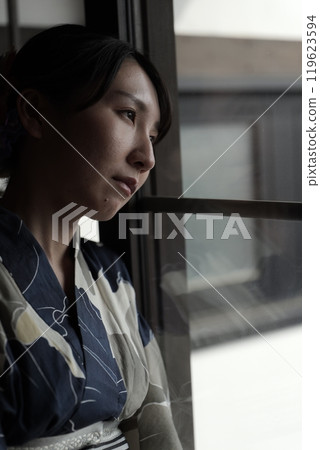 A woman in a yukata standing at a lattice door A woman in a yukata standing at a lattice door 119623594