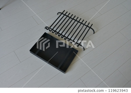 An object photo shoot of black grilles for fireplaces on a light background in the interior. 119623943