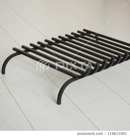 An object photo shoot of black grilles for fireplaces on a light background in the interior. 119623991