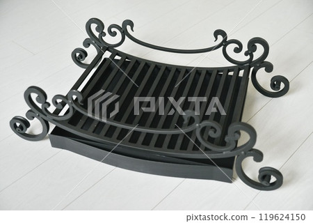 An object photo shoot of black grilles for fireplaces on a light background in the interior. An object photo shoot of black grilles for fireplaces on a light background in the interior. 119624150