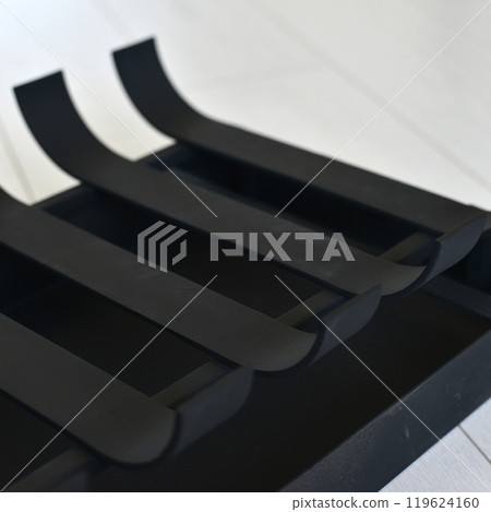 An object photo shoot of black grilles for fireplaces on a light background in the interior. 119624160