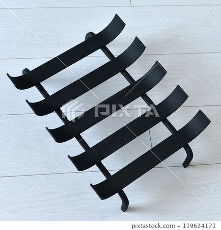 An object photo shoot of black grilles for fireplaces on a light background in the interior. 119624171