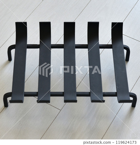 An object photo shoot of black grilles for fireplaces on a light background in the interior. An object photo shoot of black grilles for fireplaces on a light background in the interior. 119624173