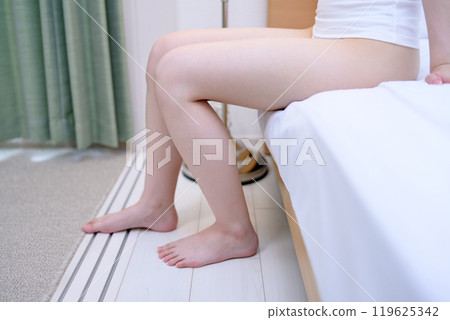 一位穿著內衣的年輕苗條女人坐在臥室的床上,美麗的雙腿,皮膚護理,飲食,足部護理 一位穿著內衣的年輕苗條女人坐在臥室的床上,美麗的雙腿,皮膚護理,飲食,足部護理 119625342