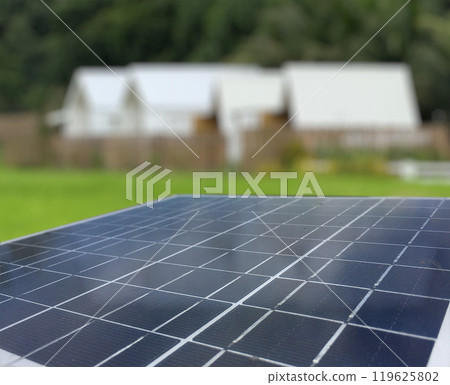 Solar panels set against a backdrop of resident, trees and a vibrant blue sky. The scene captures the harmony between renewable energy and nature, highlighting sustainability and environmental 119625802