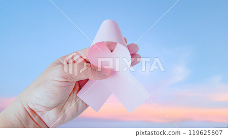 Hand holding pink ribbon, symbolizing breast cancer to enhance awareness, hope and unity, raising awareness and support for those affected by cancer, fostering understanding and prevention. Hand holding pink ribbon, symbolizing breast cancer to enhance awareness, hope and unity, raising awareness and support for those affected by cancer, fostering understanding and prevention. 119625807