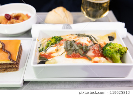 美味的商務艙餐點：義大利乳清乾酪和菠菜義大利捲配香檳和巧克力蛋糕 119625813