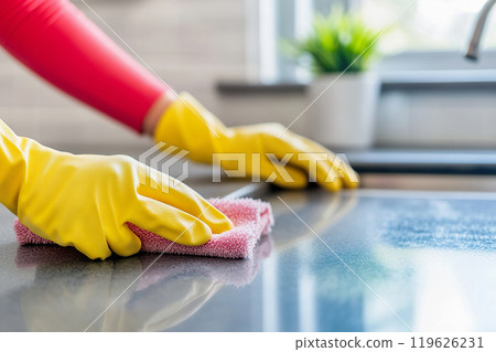 Person deep cleaning kitchen countertop with gloves and sponge, home setting. Person deep cleaning kitchen countertop with gloves and sponge, home setting. 119626231