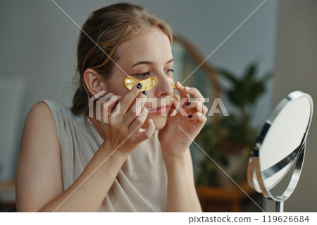 Applying Eye Patches in Modern Bathroom Setting Applying Eye Patches in Modern Bathroom Setting 119626684