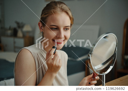 Young Woman Applying Makeup in Cozy Bedroom 119626692