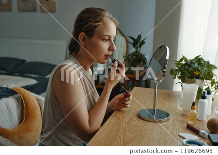 Woman Applying Makeup in Modern Bedroom Setting 119626693