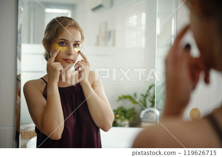 Woman Applying Skincare Mask in Bright Bathroom Woman Applying Skincare Mask in Bright Bathroom 119626715