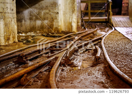 Old Rusty Railroad Tracks Running Through a Dark, Abandoned Mine Tunnel Surrounded by Stone Walls, cooper mine 119626793