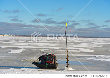 Ice fishing equipment on a frozen lake with a person in the distance Ice fishing equipment on a frozen lake with a person in the distance 119626854