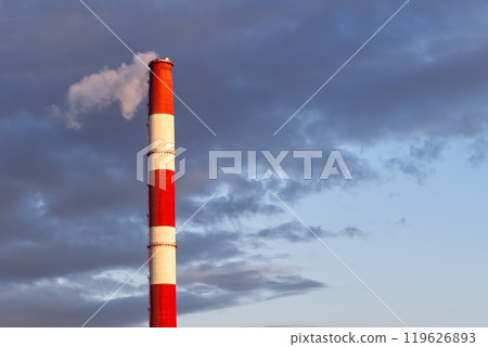 Tall Red-and-White Striped Industrial Chimney Emitting Smoke into the Atmosphere Under Cloudy Sky 119626893