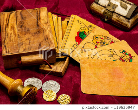 deck of medieval italian board playing cards with a blank and white card, on the table along with coins and wooden card holder deck of medieval italian board playing cards with a blank and white card, on the table along with coins and wooden card holder 119626947