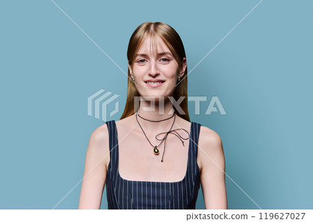 Portrait of beautiful young girl with long blond hair looking at camera on blue background Portrait of beautiful young girl with long blond hair looking at camera on blue background 119627027