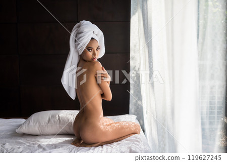 Portrait of naked Asian young woman on bed by window 119627245