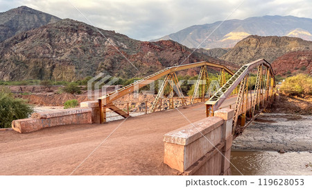 an ancient bridge over the river in a mountain landscape in Argentina 119628053