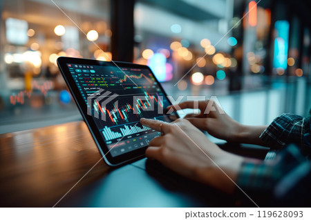 A person using a digital tablet to manage their diversified investment portfolio.A person is seated at a table, operating a tablet computer 119628093