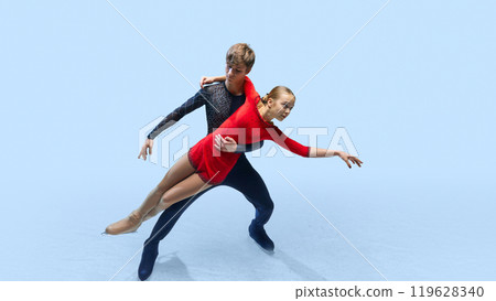 Pair of ice skaters in middle of their performance, emphasizing fluidity of their movements and power behind each stride. 119628340