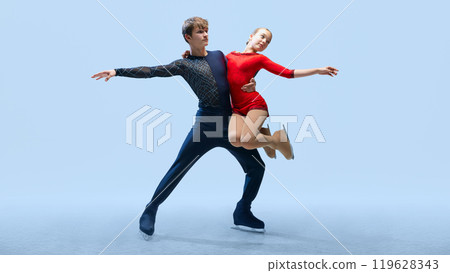 Professional ice skating partners perform difficult lift, show their elegance against cold blue background. Artistic ice dance. 119628343